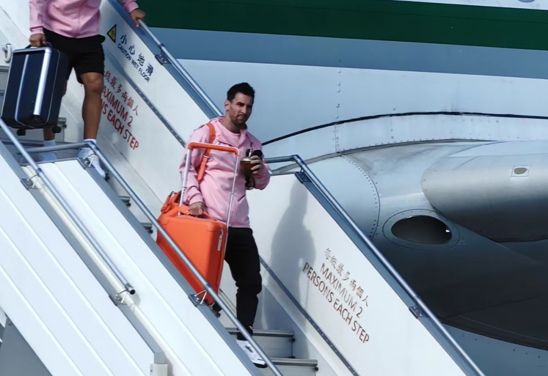 梅西一手拿着馬黛茶一手提著行李走下舷梯