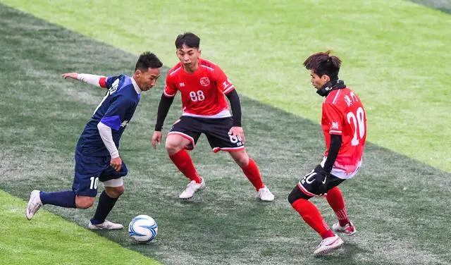 贵州村超联队球员董永恒(左)与澳门职工联队球员吴嘉华(中)、何子枫拼抢。