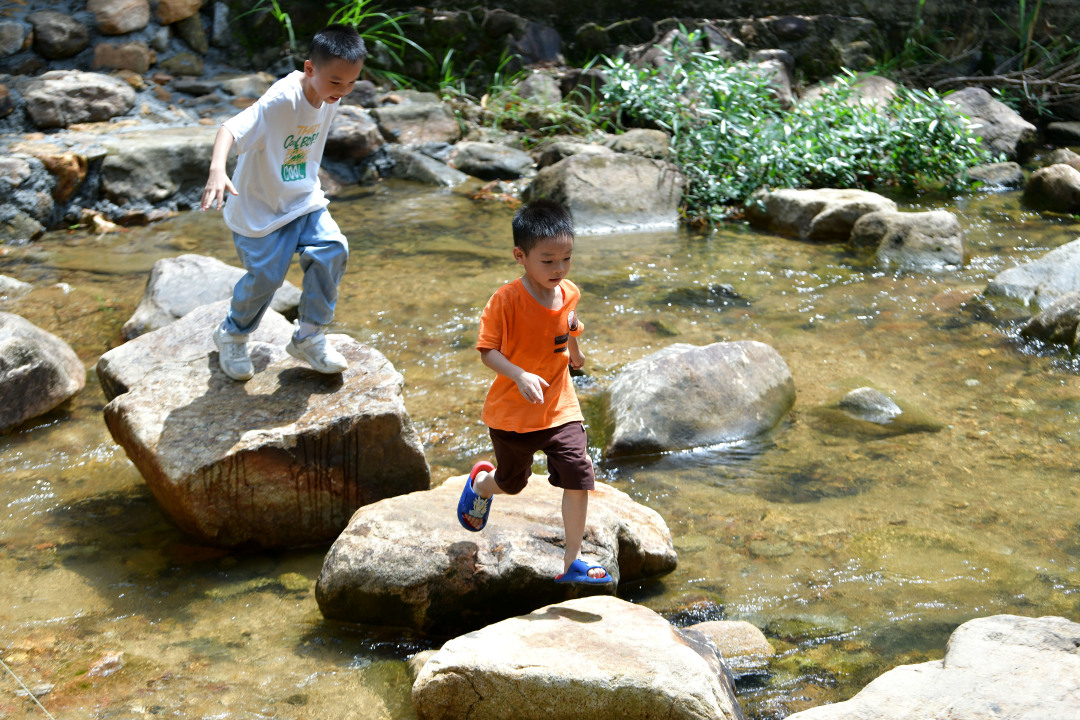 小朋友在水面上的石头上跳跃。
