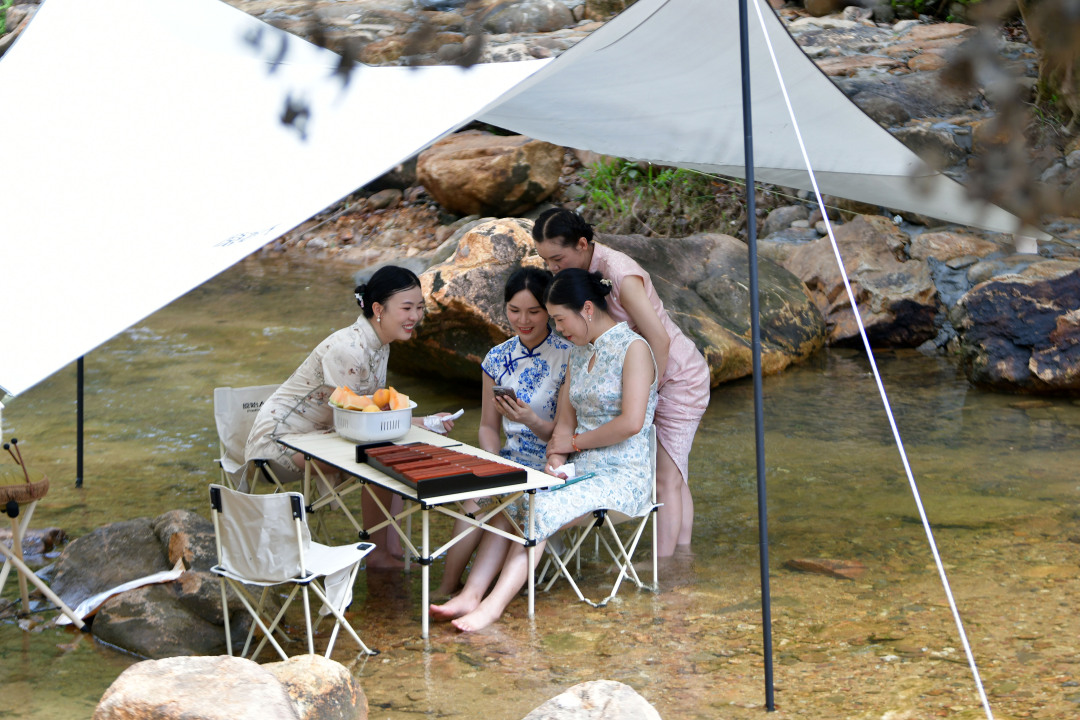 几名穿着旗袍的女子在搭着帐篷的水中闲聊。