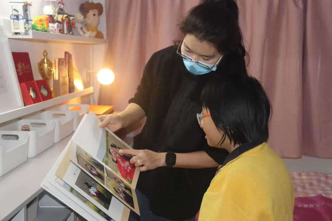 设计师给小嘉分享收纳整理的用处与技巧,然后一起欣赏全家福相册里小嘉和妈妈的照片。