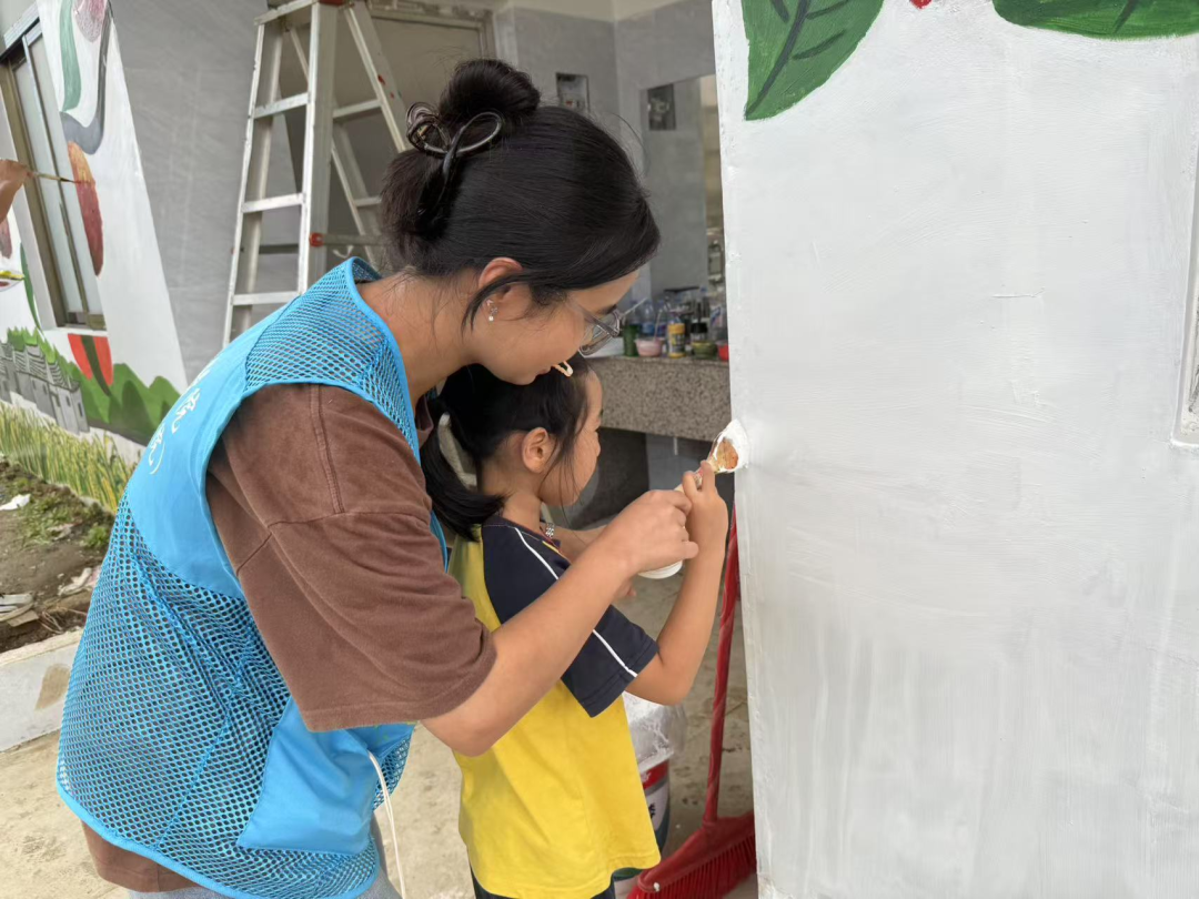 大学生志愿者手把手教孩子们墙绘.