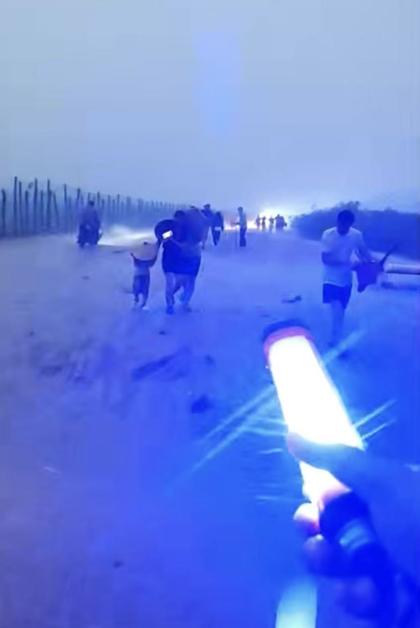 暴雨当天,张智英手持着红蓝警示灯,引导游客往岸边方向走