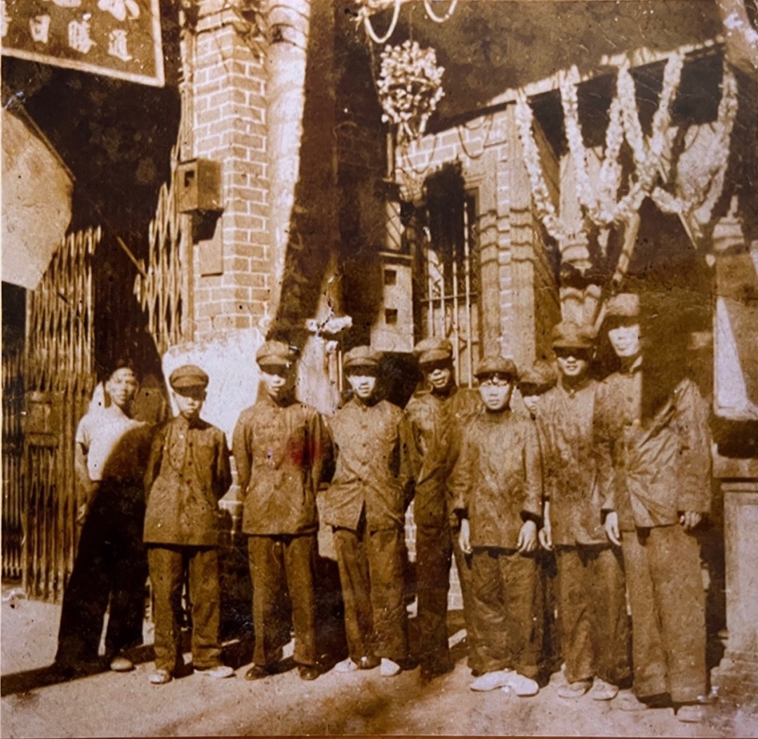 少年梁卓镇(前排右三)和工友们一起在越华报门前合影。旧照翻拍