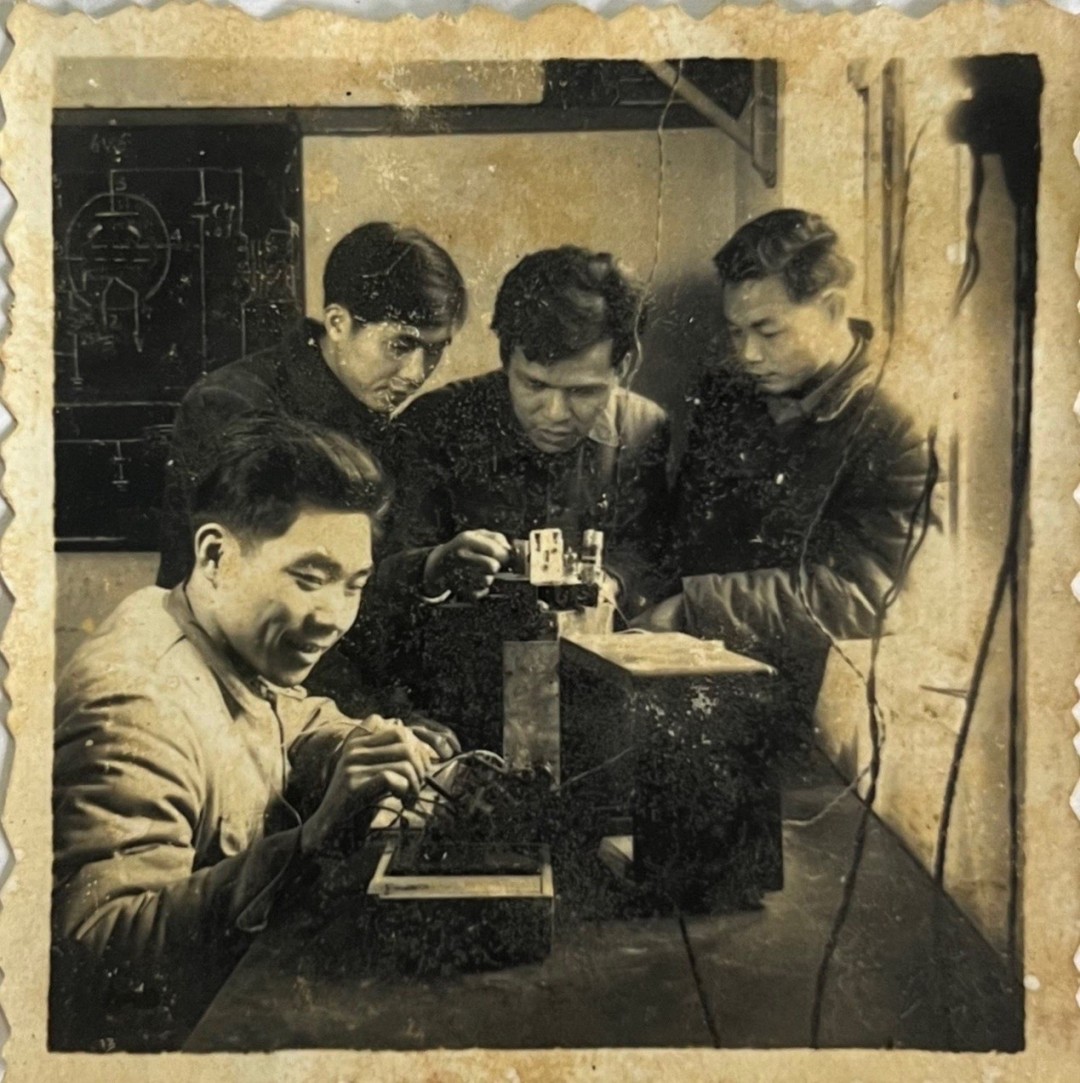 梁卓镇(左一)在教年轻人接收电稿。旧照翻拍