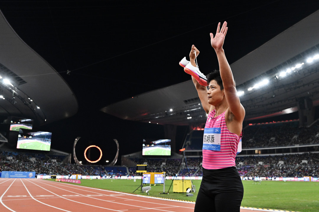 2025年11月20日,广东奥林匹克体育中心,十五运会田径项目男子4乘100米接力决赛,比赛后广东队员苏炳添高举战靴向现场观众告别。