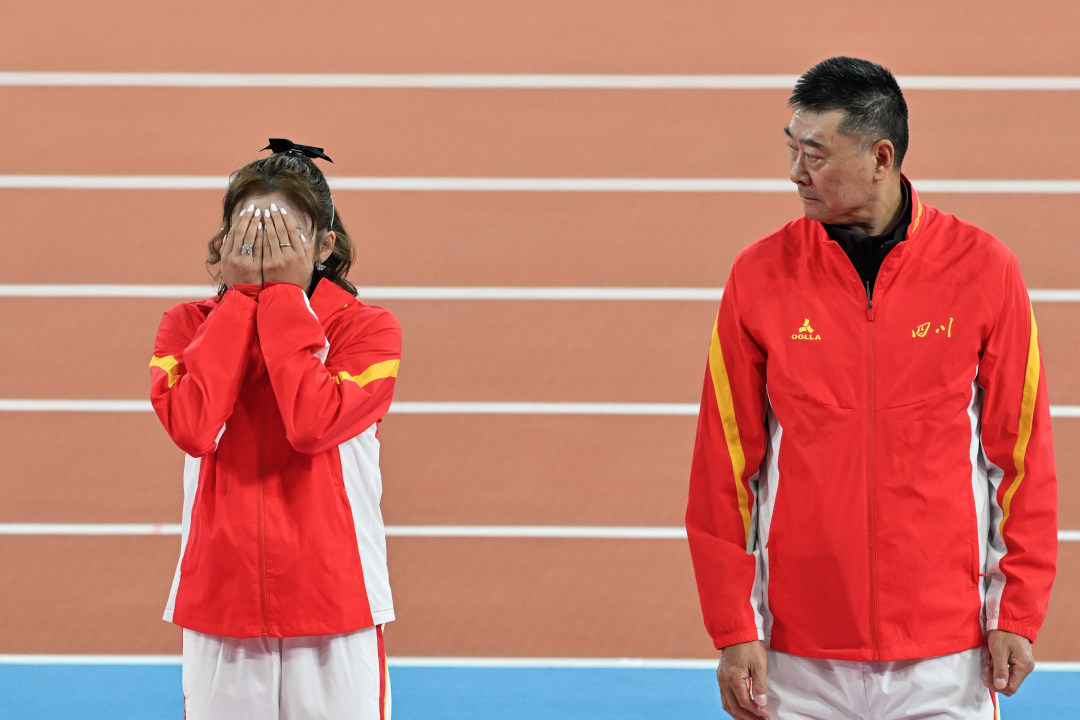 2025年11月19日,广东奥林匹克体育中心,十五运会田径项目女子100栏决赛颁奖仪式,获得银牌的四川选手吴艳妮(左)在颁奖台上掩面。