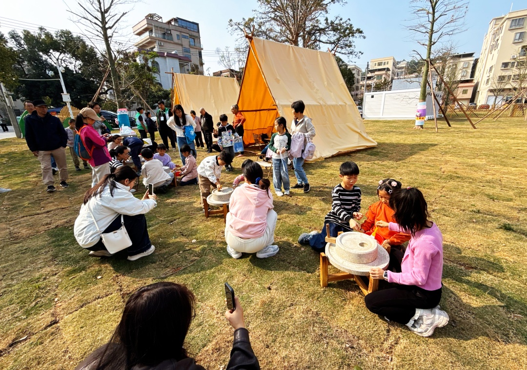 2026年1月28日,深湾村“稻里·深湾”农业园,小朋友在露天营地学习使用传统石磨磨面粉。图/广州日报新花城记者:莫伟浓