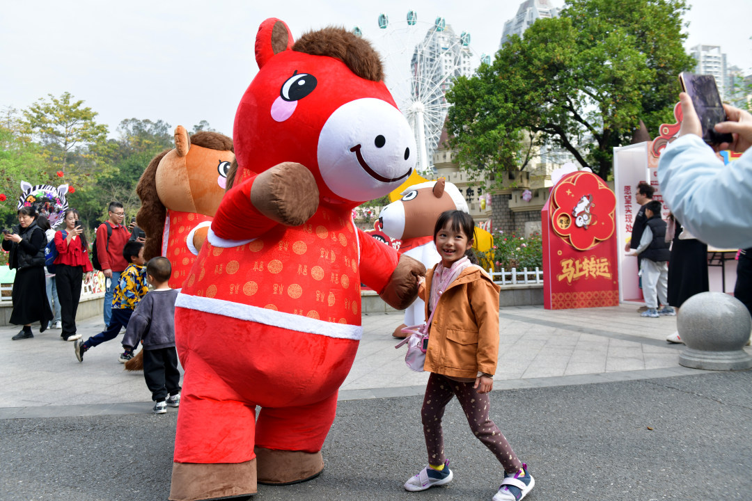 2月11日,春节期间,广州动物园化身为一座“马”趣横生的生态乐园,这里不仅有矮马、斑马等“马家族”成员,更有“斑马线”“河马大嘴巴”等马年专属打卡点位全新上线,搭配“动物明星拜大年”人偶巡游、马年生肖游园会、“马族大揭秘”特展及动物丰容等多场特色活动轮番上演,让动物与市民一起热热闹闹过新年!图为游客与人偶合影。