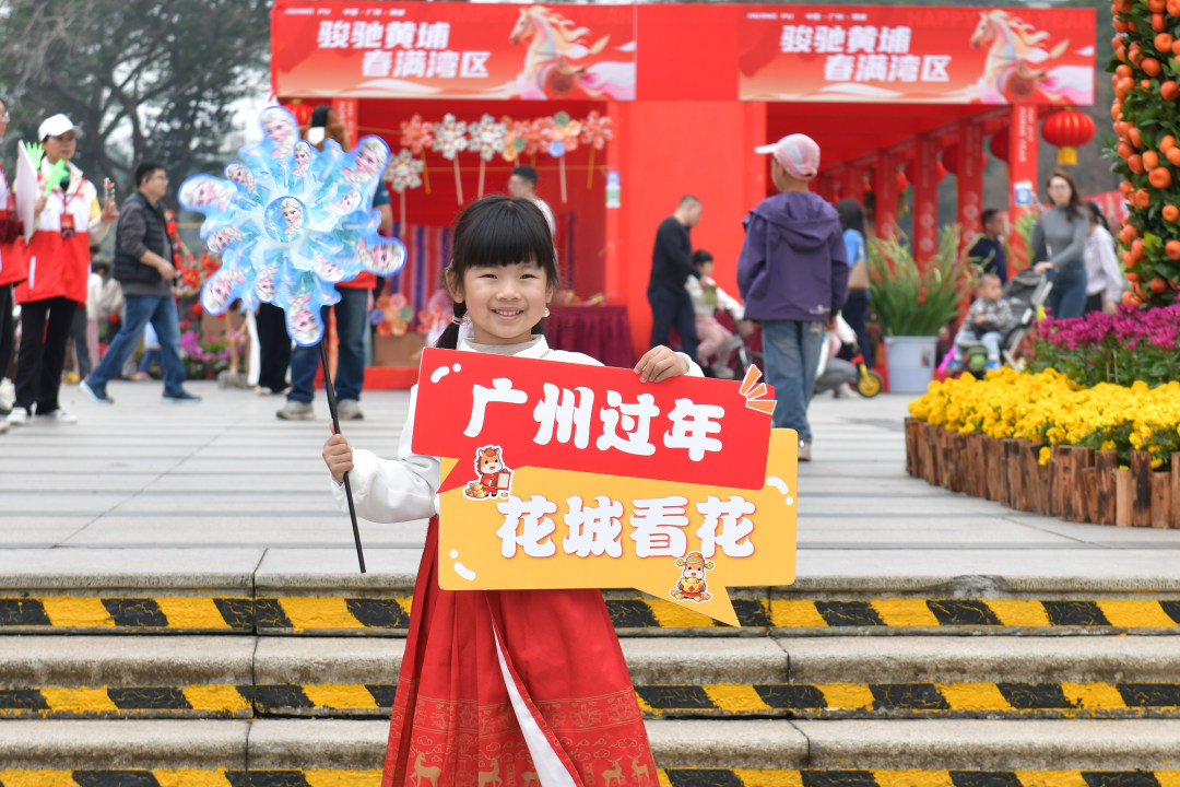 2月12日,以“骏驰黄埔 春满湾区”为主题的黄埔迎春花市热闹开锣。图为小朋友在花市门楼前留影。