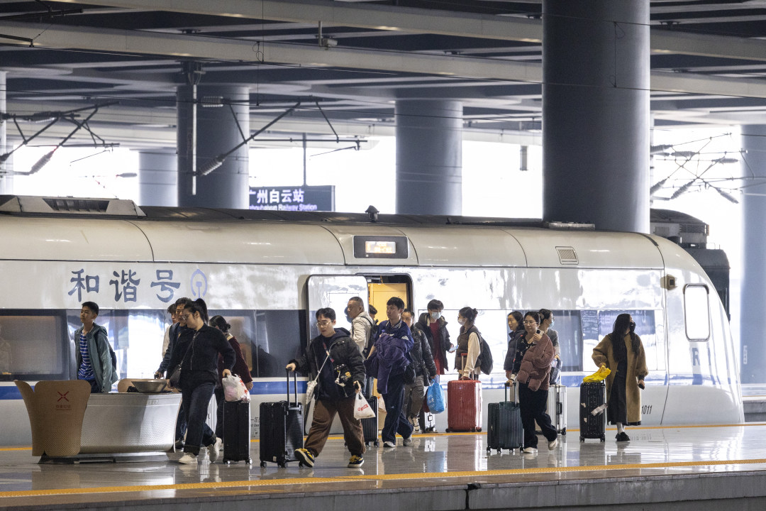 2月13日,广州白云站,旅客拖着行李出站。