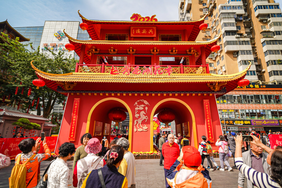 市民游客在越秀西湖花市主牌楼下拍照留念。