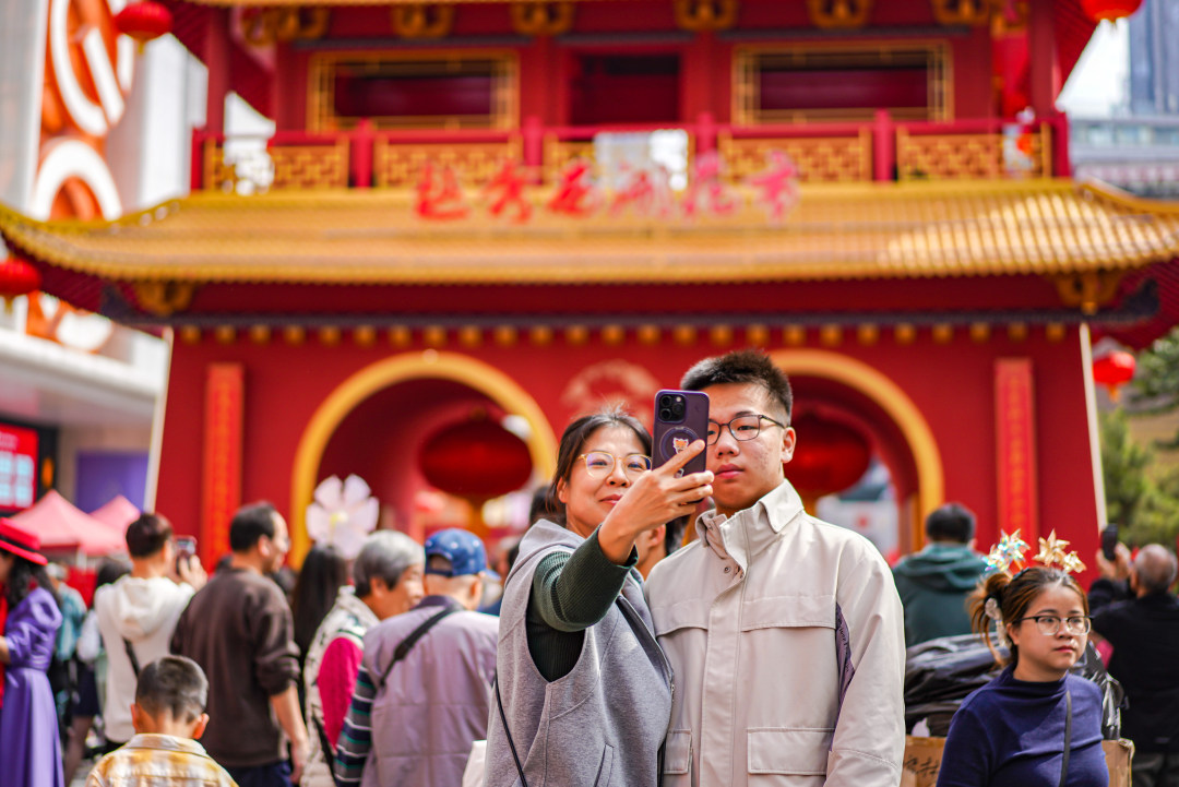市民游客在越秀西湖花市主牌楼下拍照留念。