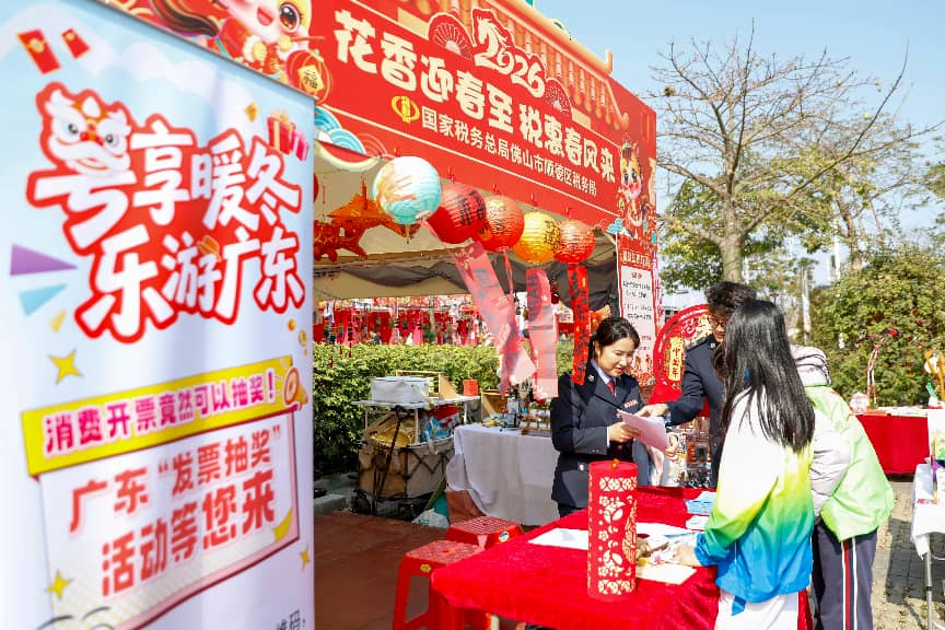 春节期间,佛山市顺德区税务局在当地迎春花市宣传“粤享暖冬 乐游广东”发票抽奖活动,游客在现场体验消费开票抽奖
