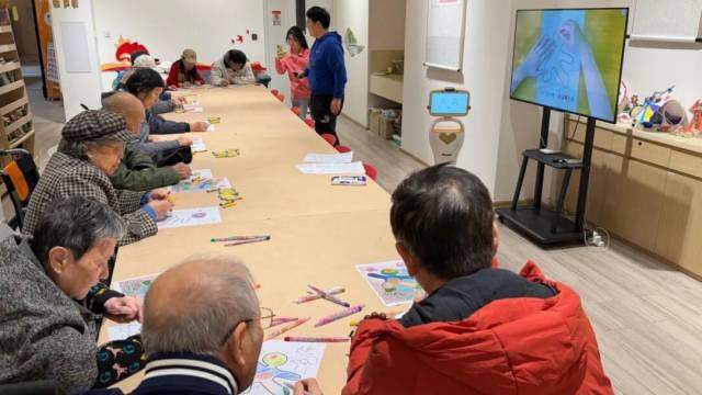 社工雷宜博在上绘画课,小丽机器人在课堂上拍照 社工雷宜博在上绘画课,小丽机器人在课堂上拍照