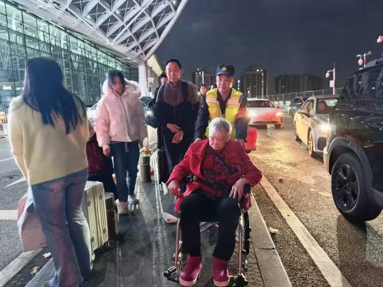 工作人员深夜为行动不便的旅客推轮椅。