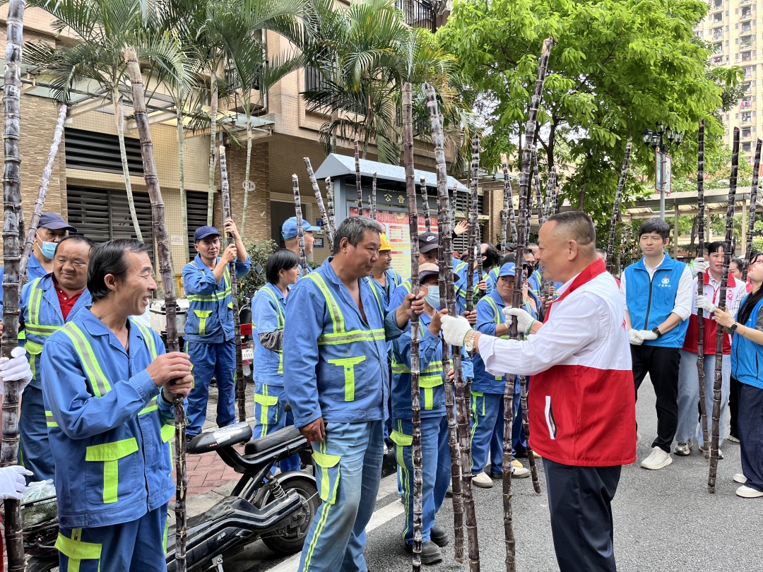 “中国好人”李桂泉带领志愿者将甘蔗免费送给环卫工人。