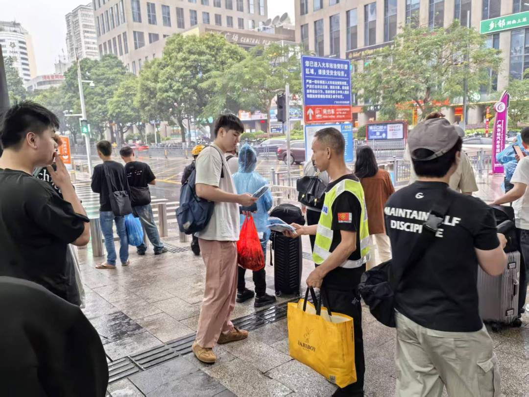 志愿者为旅客发放一次性雨衣