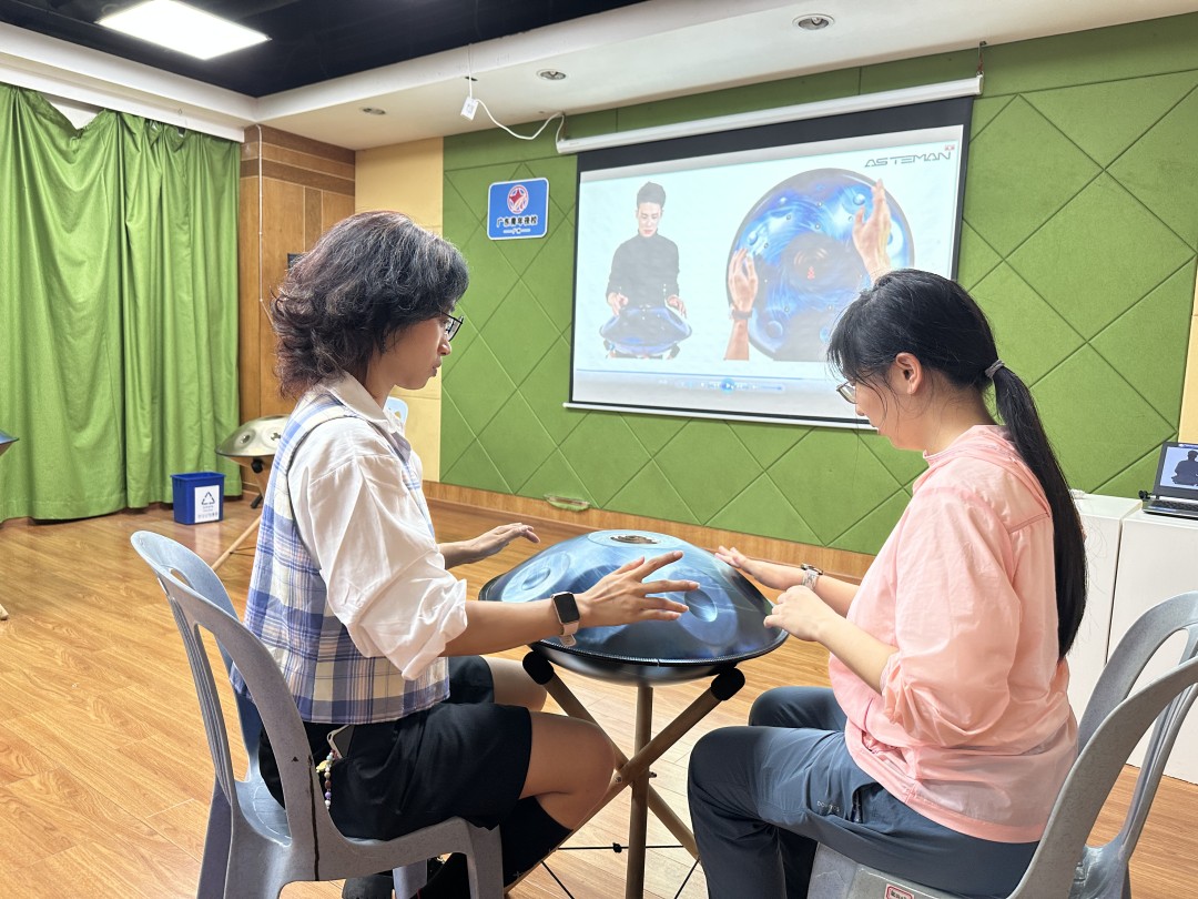 青年夜校学员轻拍手碟沉浸演奏,以空灵音律疗愈内心,释放压力与精神内耗。