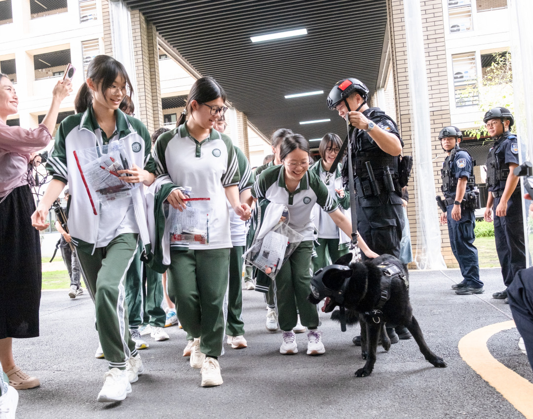 广州市培英中学云城校区考场,维持考场秩序的特警们带着警犬,跟考生们击掌加油,祝大家高考“旺旺”。考生们开心地跟帅气警犬互动。