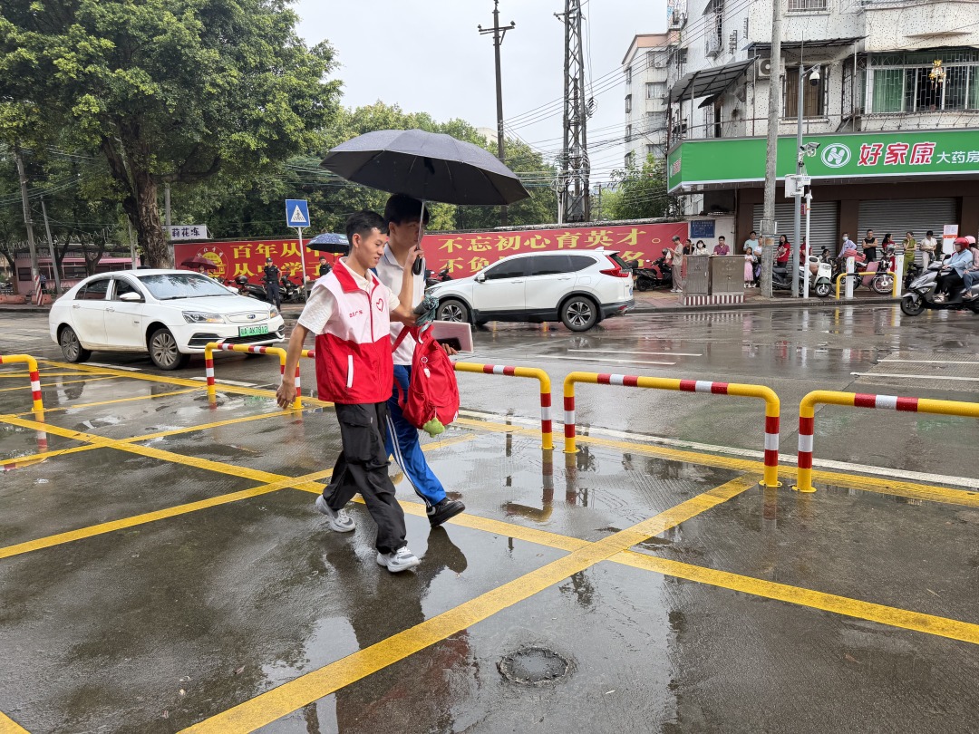 广州青年志愿者在从化区流溪中学开展爱心助考志愿服务活动,志愿者撑伞护送考生入场。