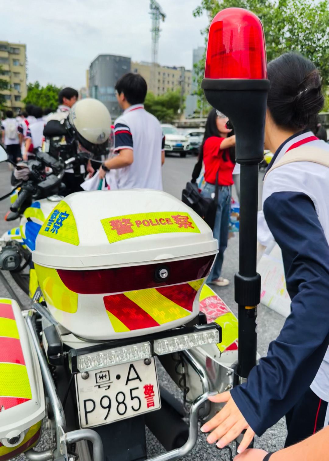 广州市培英中学云城校区考场门口,一辆车牌号为粤
AP985警的交警铁骑专门来到考场送考,给考生们送上祝福。不少同学经过时都摸摸车牌,沾沾喜气。