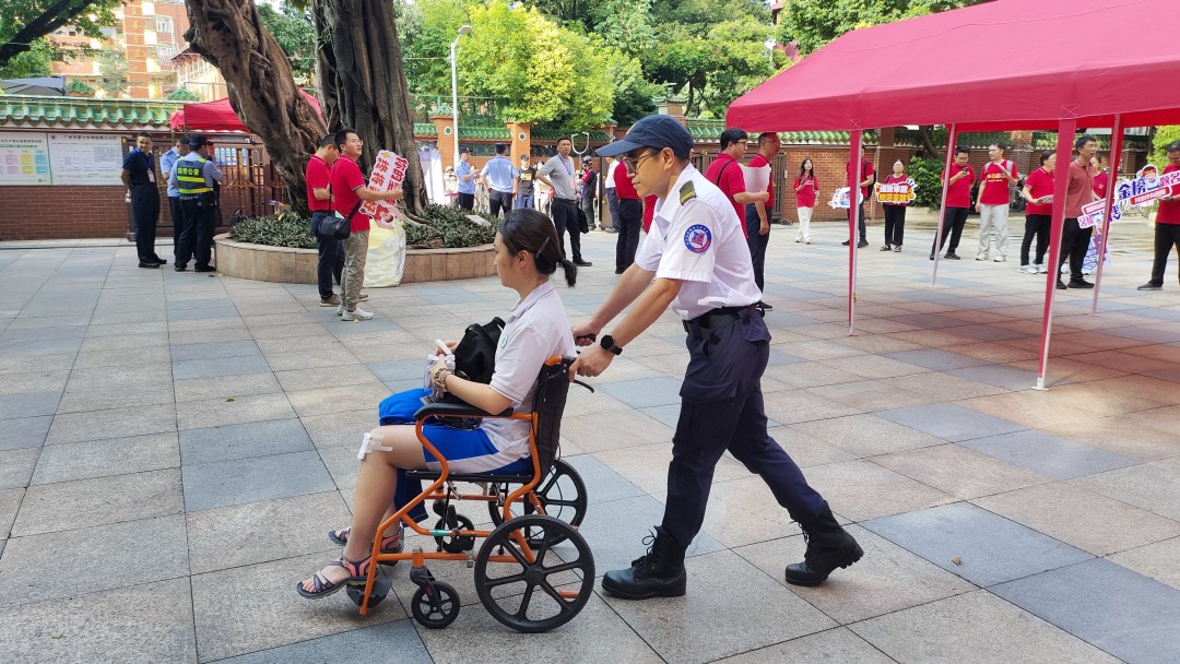 广州市越秀区暐杰志愿服务工作中心青年志愿者为特殊考生提供轮椅陪护服务,护送考生进入考场。