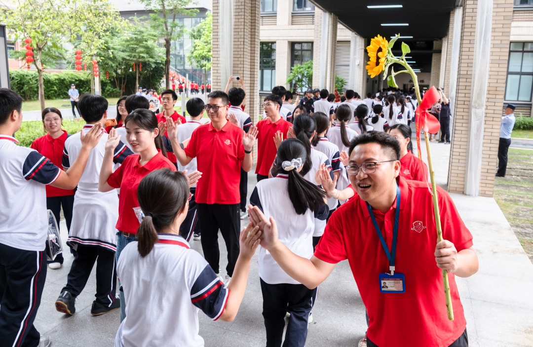 广州市培英中学云城校区考场,广州市亚加达外国语高级中学送考老师和考生击掌加油。