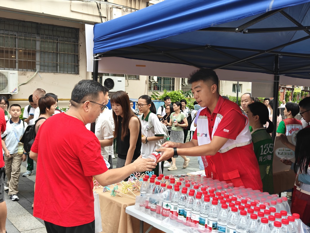 农夫山泉股份有限公司青年志愿者在广州市十七中学考点为考生家长送上饮用水,提醒家长注意防暑补水。