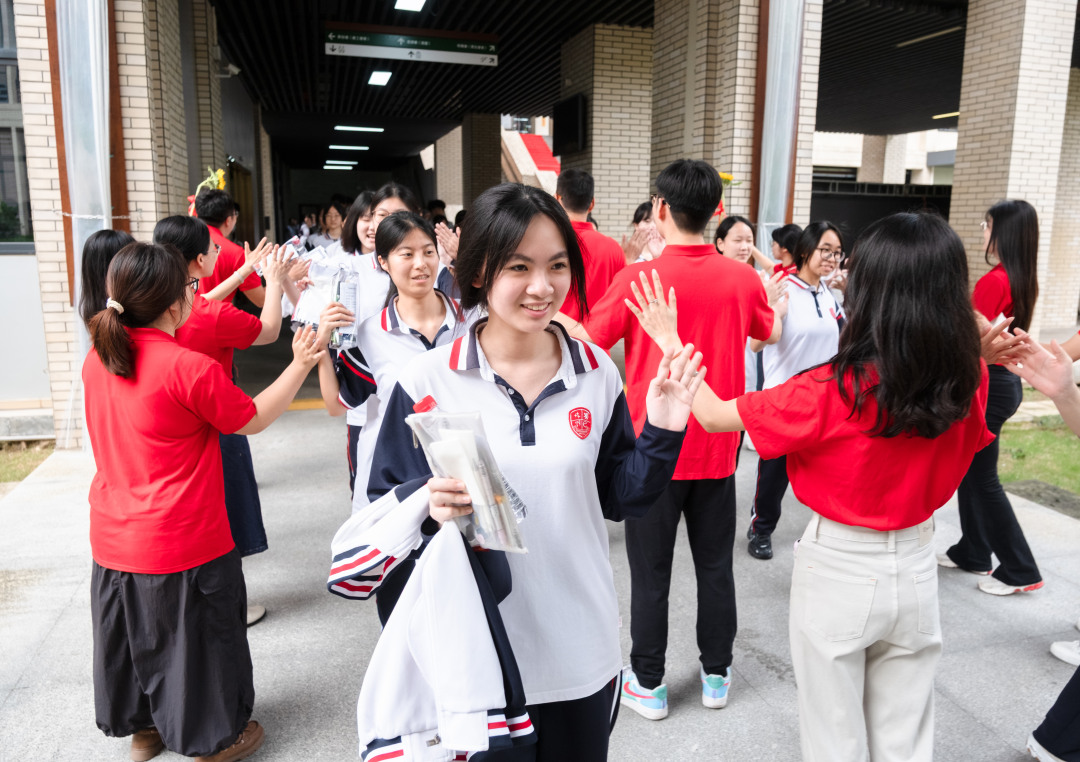 广州市培英中学云城校区考场,广州市亚加达外国语高级中学送考老师和考生击掌加油。