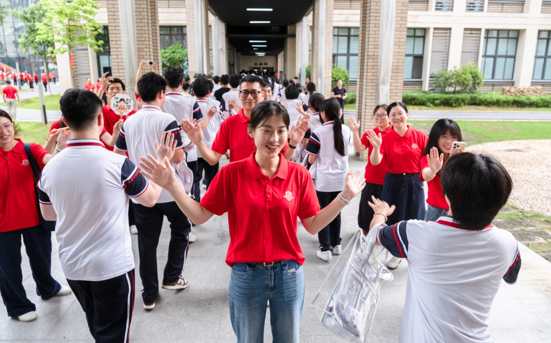 广州市培英中学云城校区考场,广州市亚加达外国语高级中学送考老师和考生击掌加油。