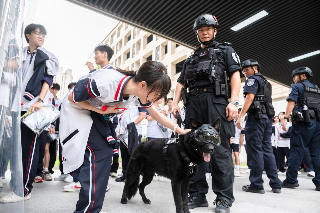广州市培英中学云城校区考场,维持考场秩序的特警们带着警犬,跟考生们击掌加油,祝大家高考“旺旺”。考生们开心地跟帅气警犬互动。