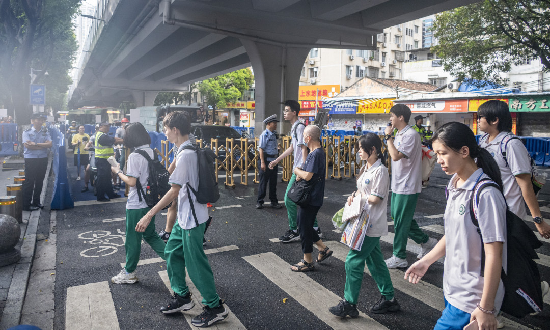 6月8日上午7点50分,前往海珠外国语实验中学考点的考生走过斑马线,两边有临时活动栅栏保障他们的通行安全。高考期间该考点附近路段实行交通临时管控措施,为考生提供方便和安全。图/广州日报新花城记者:廖雪明