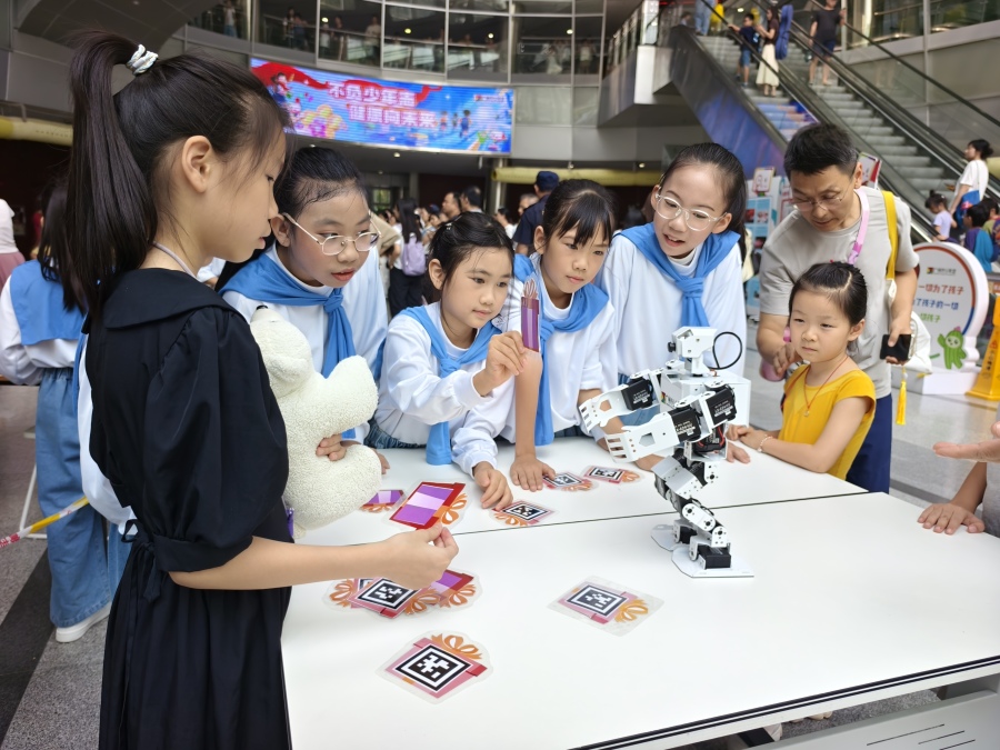 由广州市少年宫师生编程的机器人与孩子们互动。