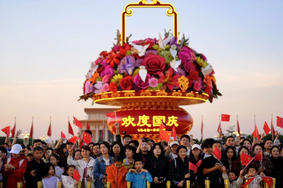 2025年10月1日，在北京天安门广场，人们观看升国旗仪式后挥舞国旗。
