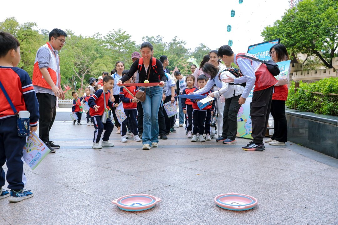 在“四平八稳”关卡里,孩子们需小心翼翼地端着挖有小洞的大圆盘将代表着“鱼骨头”“过期药品”“一次性饭盒”的小球运送到垃圾桶位置,并精准分类投放。(通讯员供图)